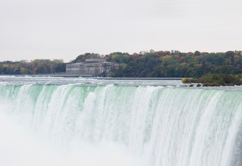 Beautiful and impressive panorama of the Niagara Falls in Ontario (Canada) on a bright colorful (red, orange, yellow) autumn day with water crashing down the falls onto rocks creating lots of mist