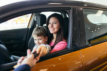 Mother and son buying a new car at the car showroom.