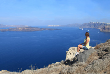 Young woman enjoying view of a volcano from the top of Santorini island, Greece