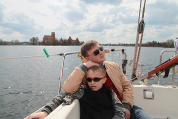 Father and son have a trip in sailboat on a lake by Trakai castle in Lithuania