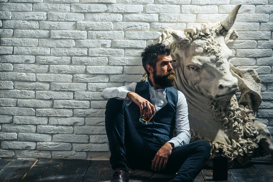 Bearded man collector drink whiskey at plaster statue.