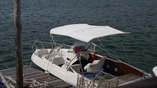 white ski boat docked in a wood pier with sea water in background.