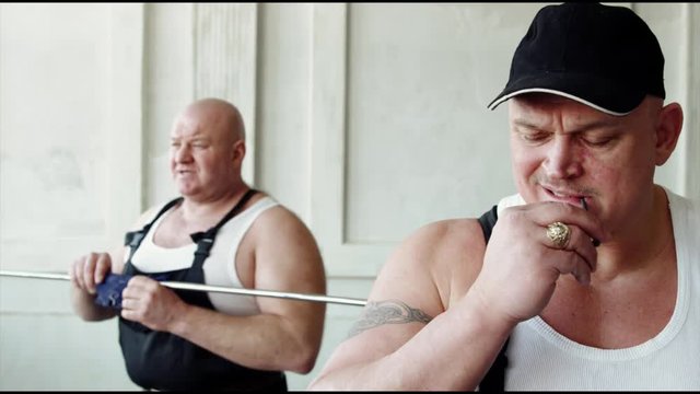 a thick and pumped-up man bends an iron stick with his teeth, next is a builder standing like a bandit or a gangster who holds a toothpick in his hands