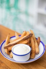 Close up on a dish of mayonnaise on a plate of french fries