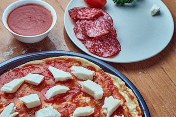 Homemade raw pizza pepperoni, ingredients for pizza, tomato sauce, mozzarella cheese, salami