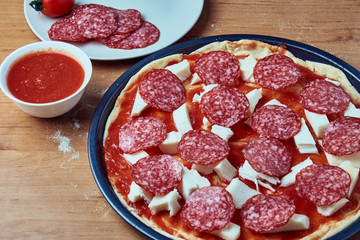 Homemade raw pizza pepperoni, ingredients for pizza, tomato sauce, mozzarella cheese, salami