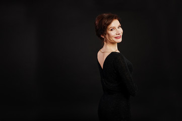 Fototapeta premium Elegance woman in black evening dress posed on studio isolated on black.