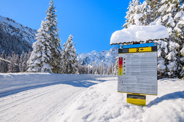 TATRA MOUNTAINS, POLAND - MAR 22, 2018: Sign informing of avalanche risk on road to Morskie Oko lake in winter time. This place is most popular tourist destination in Polish part of Tatra Mountains. © pkazmierczak