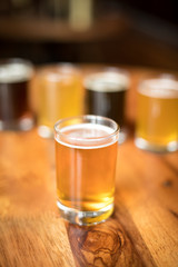 Glass of India Pale Ale, with a flight of craft beers in the blurry background