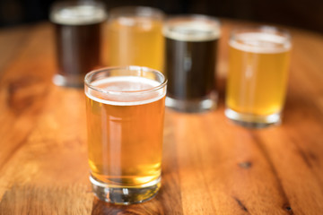 Glass of India Pale Ale, with a tasting flight of craft beers in the background