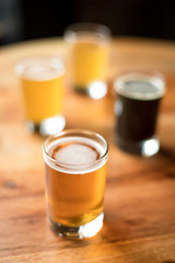 Glass of India Pale Ale with a flight of three craft beers in the background