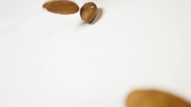 Almonds falling on white background