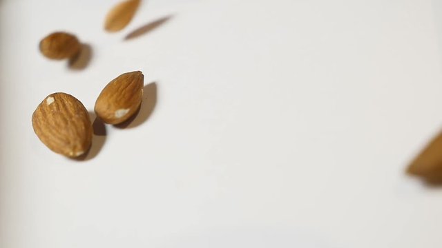 Almonds falling on white background