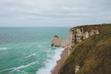 Fototapeta na wymiar Colorful vertical limestone cliffs with sea coast turquoise waters of the bay near Etretat in Normandy, France