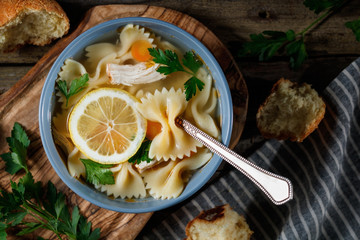Top view of a chicken soup with pasta. Rustic style.