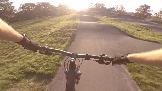 Riding bicycle on city asphalt pump track, first person point of view POV. Man riding on tarmac track, extreme sports from first person perspective. Gimbal stabilized video GOPRO HERO5.