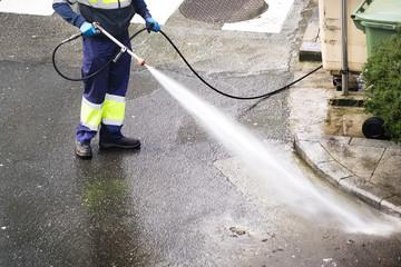 sweeper gardener  cleaning  the city street with pressure water
