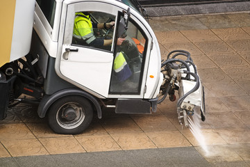 sweeper gardener  cleaning  the city street with pressure water