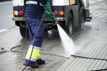 sweeper gardener  cleaning  the city street with pressure water