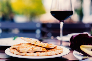 Griechisches Pita Brot mit Gewürzen vom Grill mit Rotwein im Garten serviert