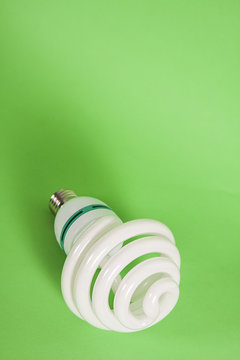 Energy saving spiral electric bulb on green background