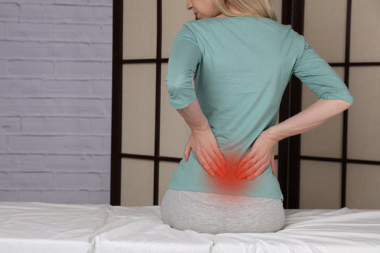 Woman suffering from low back pain. Incorrect sitting posture problems, Muscle spasm, rheumatism. Pain relief, chiropractic concept.