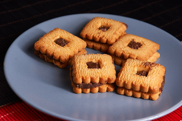 Chocolate cookies on gray plate on style red and black table, closeup.