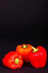 Three ripe red peppers isolated on a black background