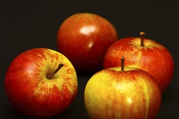 Four red ripe apples isolated on a black background