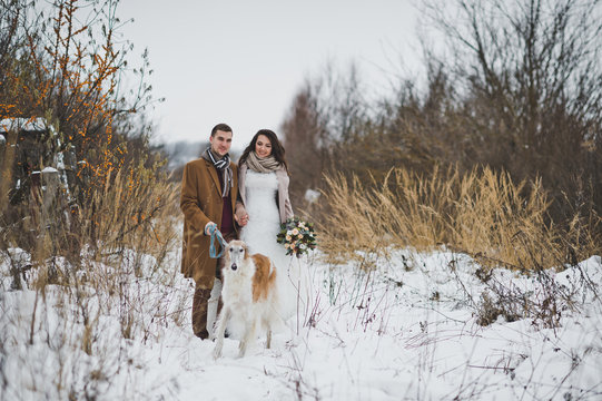 The newlyweds are standing against the background of a winter red shru