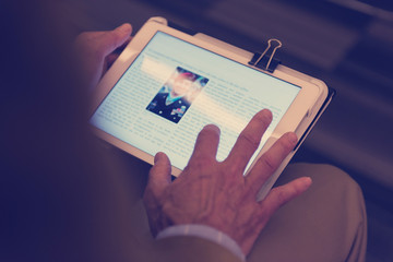 Closeup of mature hands holding tablet.