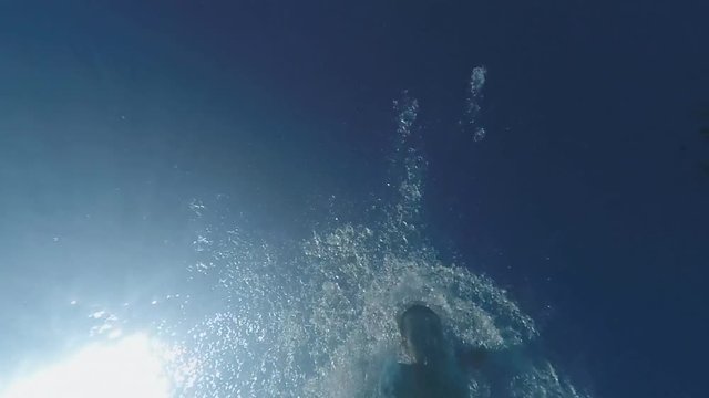 SLOW MOTION: Man diving in swimming pool, sea or ocean underwater view. Swimmer jumping in to the water. Sun underwater over blue sunny sky background. Shot with GOPRO HERO4 1080 FullHD 120fps video.