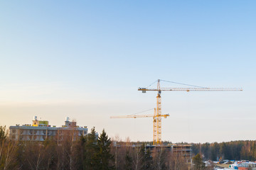 Construction cranes at a construction site at sunset in early spring