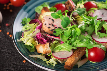 Fresh vegetable salad with grilled chicken breast - tomatoes, radish and mix lettuce leaves. Chicken salad. Healthy food. Black background. Top view