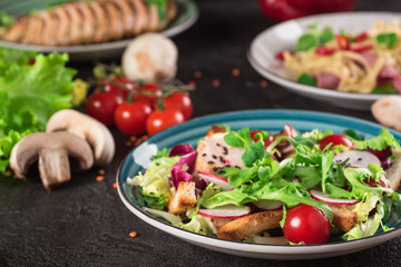 Fresh vegetable salad with grilled chicken breast - tomatoes, radish and mix lettuce leaves. Chicken salad. Healthy food. Black background. Top view