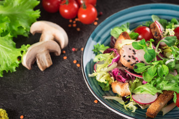 Fresh vegetable salad with grilled chicken breast - tomatoes, radish and mix lettuce leaves. Chicken salad. Healthy food. Black background. Top view