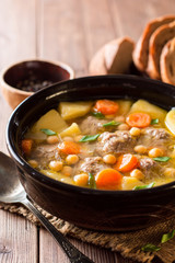 Soup with meatballs, vegetables and chickpea on wooden table