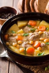Soup with meatballs, vegetables and chickpea on wooden table