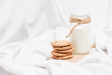 Photo of a jar of milk and cookies on a wooden board