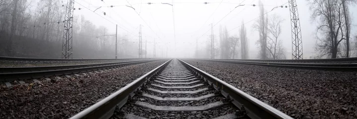 Poster Het spoor in een mistige ochtend. Veel rails en dwarsliggers gaan de mistige horizon in. Fisheye-foto met verhoogde vervorming © mehaniq41