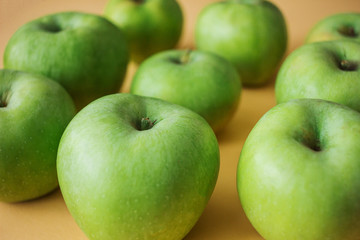 Ripe green apples on a pastel peach background