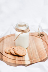 Photo of a milk and cookies on a wooden board and white background