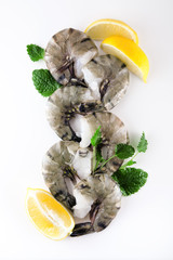 fresh king prawns with lemon and lemon balm on white wooden kitchen plate can be used as background