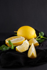 bright yellow lemons, slices, rustic food photography on dark slate plate kitchen table can be used as background