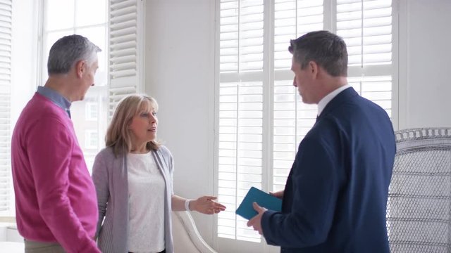 Mature couple agree on a property with real estate agent and shake hands