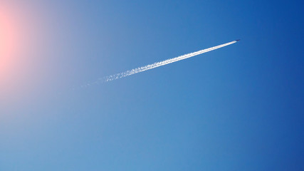 airplane and white track on a blue sky, toned
