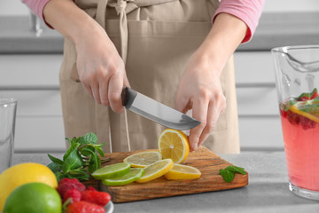 Woman preparing fresh lemonade on table