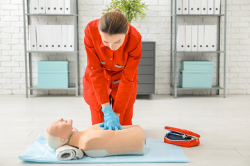 Woman practicing CPR on mannequin at first aid class