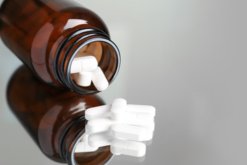 Bottle with pills on reflective surface