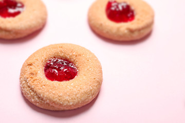 Tasty cookies with jam on color background